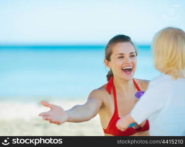 Happy mother playing with baby girl on beach