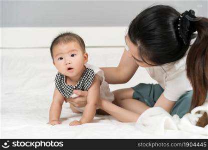 happy mother playing with baby on a bed at home