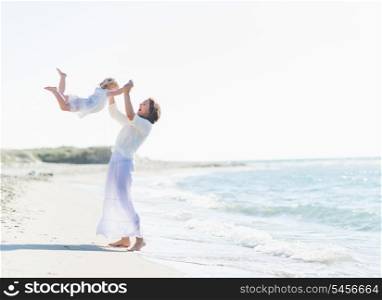 Happy mother playing with baby on beach