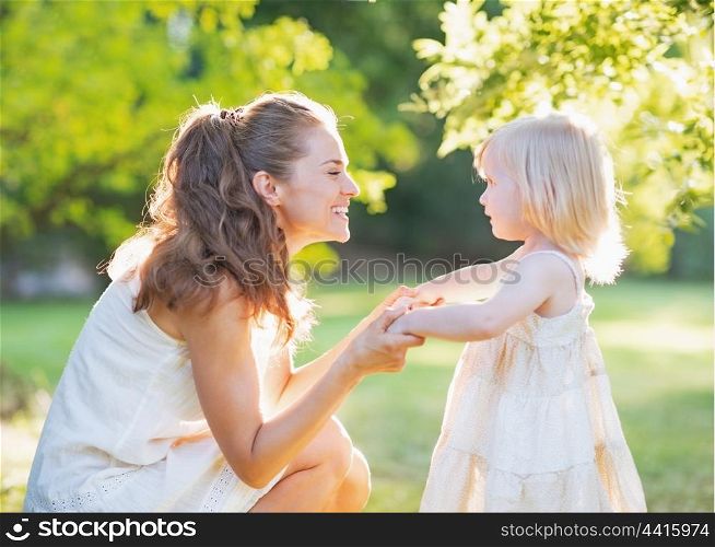 Happy mother playing with baby outdoors