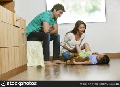 Happy mother playing with daughter while father sitting besides