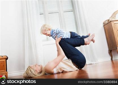 Happy mother playing with her cute loving baby at home