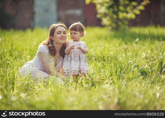 Happy mother sitting with daughter in park outdoors. Happy mother with baby