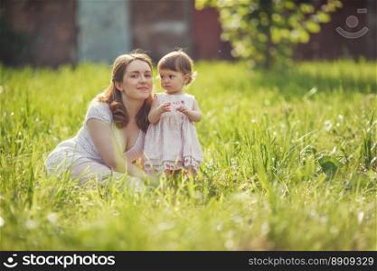 Happy mother sitting with daughter in park outdoors. Happy mother with baby