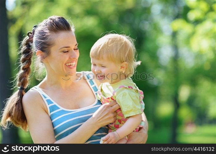 Happy mother tickling baby outside