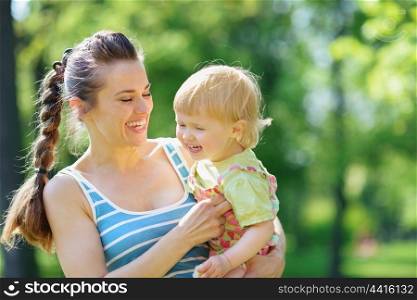 Happy mother tickling baby outside