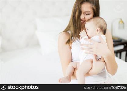 Happy mother with baby on bed