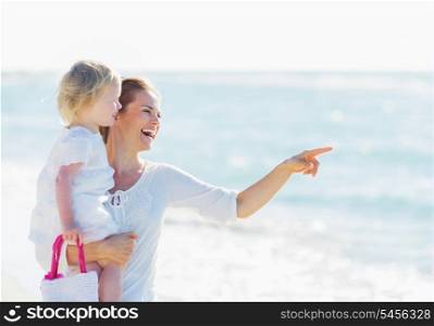 Happy mother with baby pointing on copy space