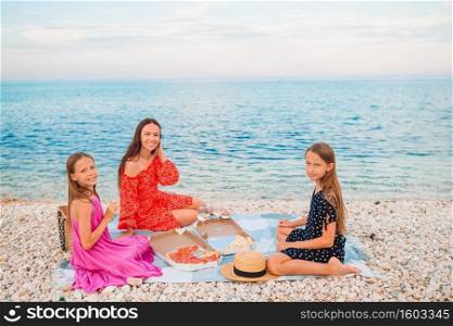 Happy mother with children on the beach on picnic. Family having a picnic on the beach