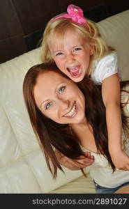 happy mother with daughter at home on white sofa