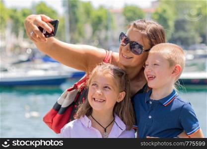 happy mother with her children are taking a selfie in a sunny day