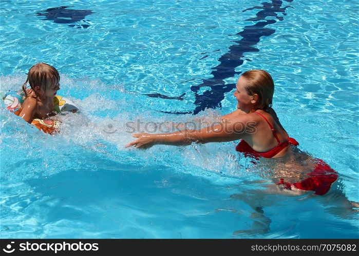 Happy mother with her daughter enjoy vacations in swimming pool. Happy family. Family enjoying summer vacations. People enjoying family holiday. Female team. Mother catching her daughter jumping into swimming pool. Happy holidays