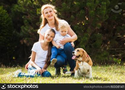 Happy mother with her daughter, little son and beagle dog for a walk