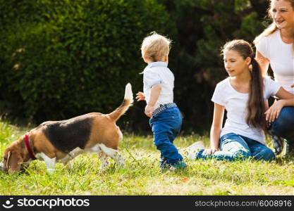 Happy mother with her daughter, little son and beagle dog for a walk