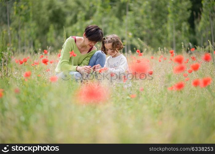 Happy mother with her little daughter in poppy field