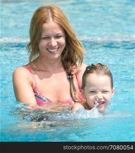 happy mother with her son in a swimming pool