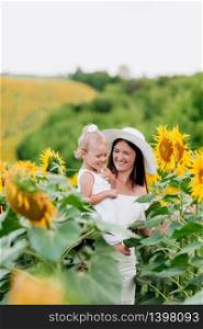 Happy mother with the daughter in the field with sunflowers. mom and baby girl having fun outdoors. family concept. selective focus.. Happy mother with the daughter in the field with sunflowers. mom and baby girl having fun outdoors. family concept. selective focus