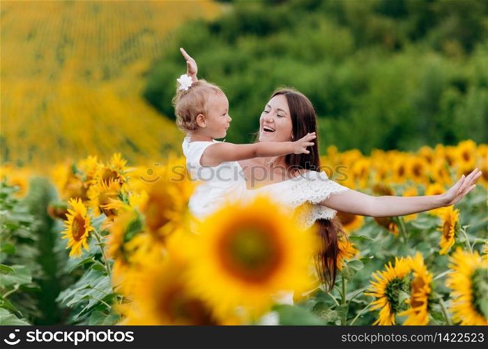 Happy mother with the daughter in the field with sunflowers. mom and baby girl having fun outdoors. family concept. selective focus. Happy mother with the daughter in the field with sunflowers. mom and baby girl having fun outdoors. family concept. selective focus.