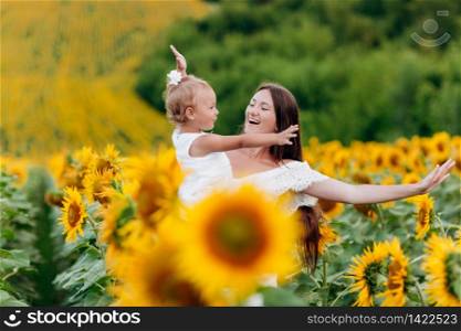 Happy mother with the daughter in the field with sunflowers. mom and baby girl having fun outdoors. family concept. selective focus. Happy mother with the daughter in the field with sunflowers. mom and baby girl having fun outdoors. family concept. selective focus.