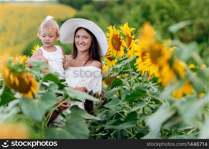 Happy mother with the daughter in the field with sunflowers. mom and baby girl having fun outdoors. family concept. Happy mother with the daughter in the field with sunflowers. mom and baby girl having fun outdoors. family concept.