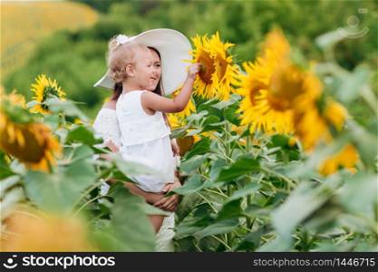 Happy mother with the daughter in the field with sunflowers. mom and baby girl having fun outdoors. family concept. selective focus.. Happy mother with the daughter in the field with sunflowers. mom and baby girl having fun outdoors. family concept. selective focus