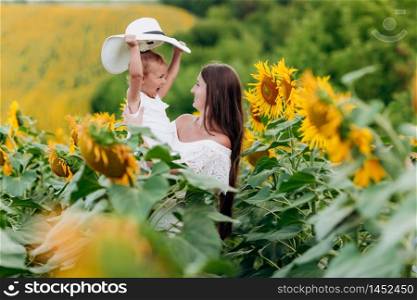 Happy mother with the daughter in the field with sunflowers. mom and baby girl having fun outdoors. family concept. Happy mother with the daughter in the field with sunflowers. mom and baby girl having fun outdoors. family concept.