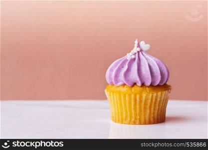 Happy Mothers Day, cute cupcake with small white heart on purple cream on pink background
