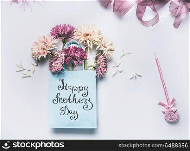 Happy Mothers day! Greeting card with fresh lovely flowers bunch in blue paper shopping bag with pen on white desktop background, Top view , copy space