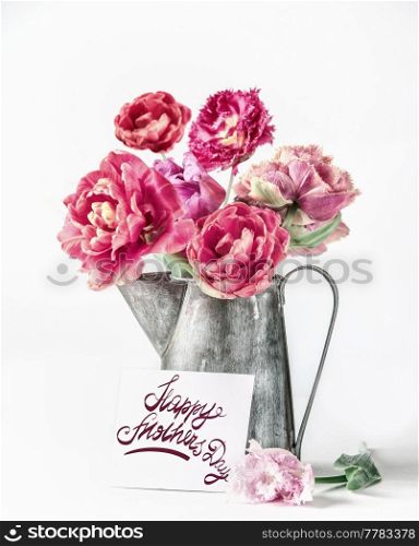 Happy mothers day greeting with pink peonies flowers bouquet in pitcher with greeting card and letters on white background. Celebrating with beautiful flowers bunch. Front view.