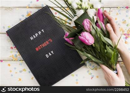 happy mothers day title board with person holding bouquet