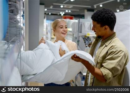Happy multiracial married family couple buying blanket for bed in furniture store. Happy multiracial couple buying blanket in store