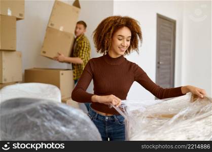 Happy multiracial young married couple packing box. Spouses moving into new home. Couple packing box moving in new home