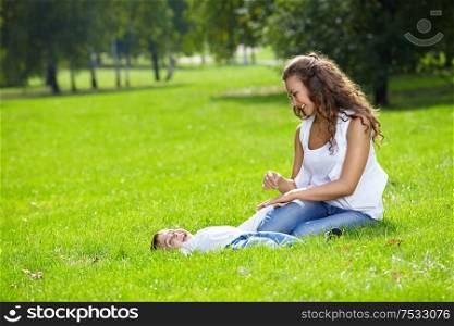 Happy mum with son on a lawn in park