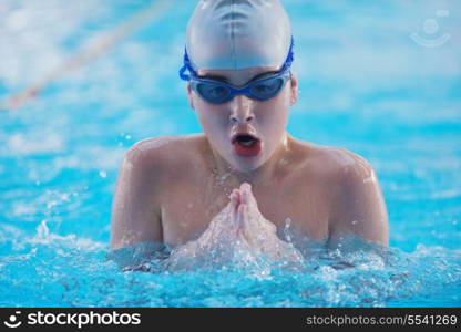 Happy muscular swimmer wearing glasses and cap at swimming pool and represent health and fit concept