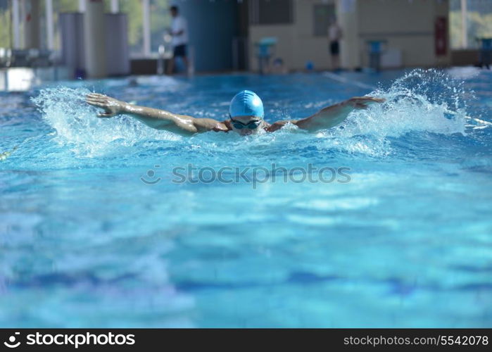 Happy muscular swimmer wearing glasses and cap at swimming pool and represent health and fit concept