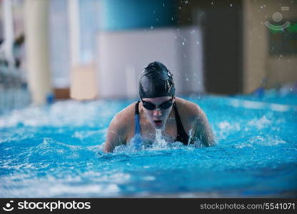 Happy muscular swimming woman wearing glasses and cap at swim pool and represent health and fit concept