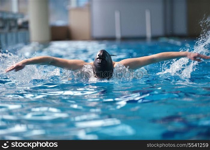 Happy muscular swimming woman wearing glasses and cap at swim pool and represent health and fit concept