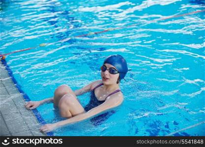 Happy muscular swimming woman wearing glasses and cap at swim pool and represent health and fit concept
