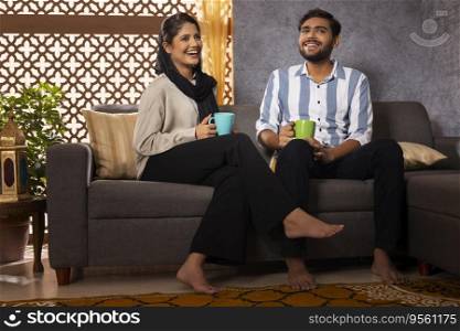 Happy Muslim couple drinking coffee in living room