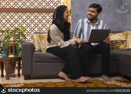 Happy Muslim couple shopping online by using laptop 