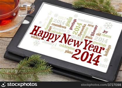 Happy New Year 2014 - word cloud on a digital tablet with a cup of tea and spruce twigs