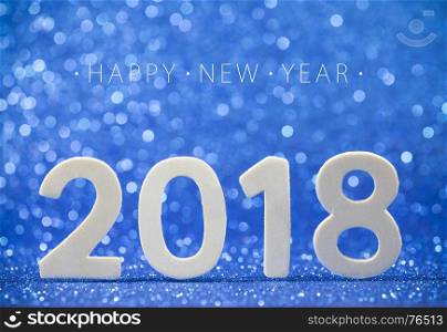 Happy New Year 2018 white wood number on blue paper with glitter lights.