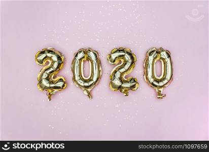 Happy New year 2020 celebration. Gold foil balloons numeral 2020 and golden stars on pastel pink background. Holiday party decoration.. Happy New year 2020 celebration. Gold foil balloons numeral 2020 and golden stars on pastel pink background. Flat lay.