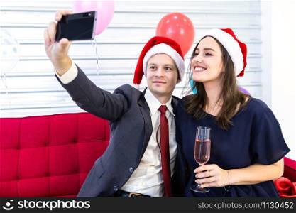 Happy new year 2020 concept, Selfie of Happy couple holding the champagne glass in Christmas and New Year&rsquo;s Eve party Christmas tree background After finishing business work