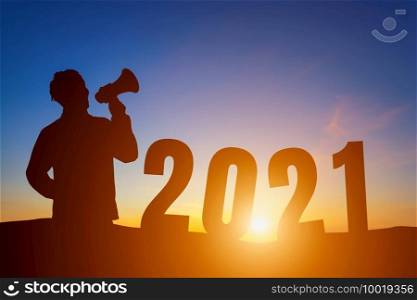 Happy New Year 2021, Silhouette a man handsome young wearing shouting with megaphone morning sunrise over the horizon background, Health and Happy new year concept.
