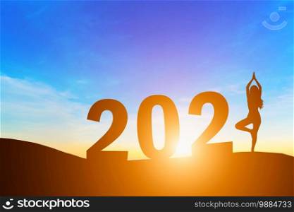 Happy New Year 2021, Silhouette woman practicing yoga early morning sunrise over the horizon background, Health and Happy new year concept.