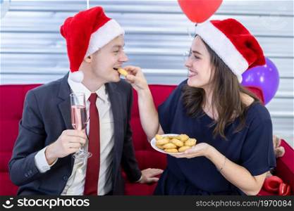 Happy new year 2022 concept,Happy couple Hold a glass of champagne and eat the cookies in Christmas and New Year&rsquo;s Eve party After finishing business work