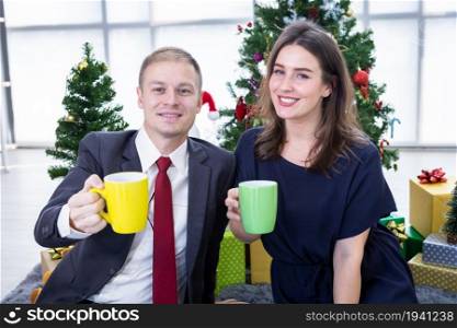 Happy new year 2022 concept, Happy couple holding the having cup of coffee,milk or chocolate in Christmas and New Year&rsquo;s Eve party Christmas tree background After finishing business work