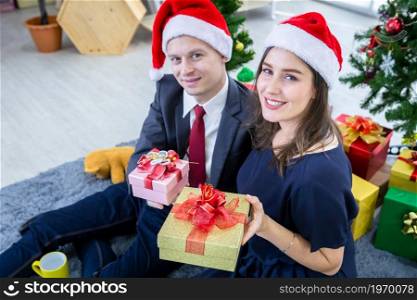 Happy new year 2022, concept,Happy couple of wrist in a business suit holding exchanging gifts and Give a present in Christmas and New Year&rsquo;s Eve party Christmas tree After finishing business work