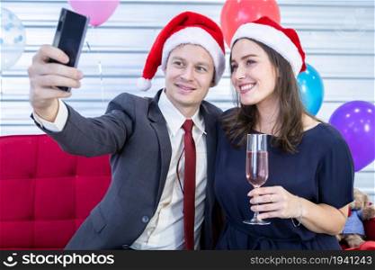 Happy new year 2022 concept, Selfie of Happy couple holding the champagne glass in Christmas and New Year&rsquo;s Eve party Christmas tree background After finishing business work